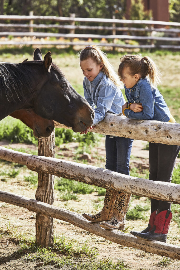 Two girls petting horses at the on-site stables at Bishop's Lodge
