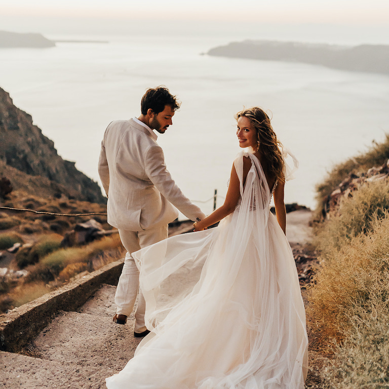 Bride and groom descending stairs toward the sea