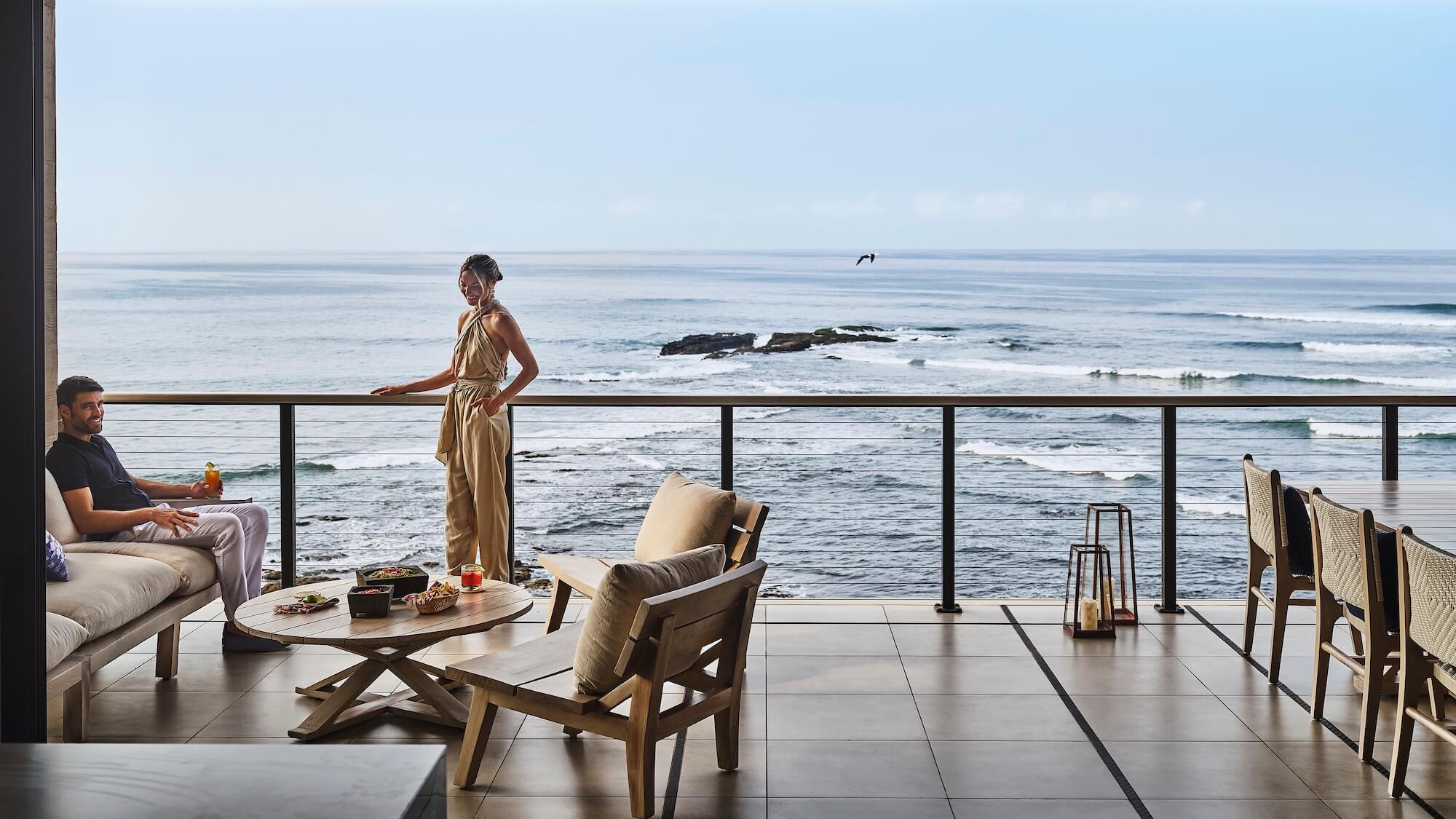 Man and woman on balcony overlooking ocean