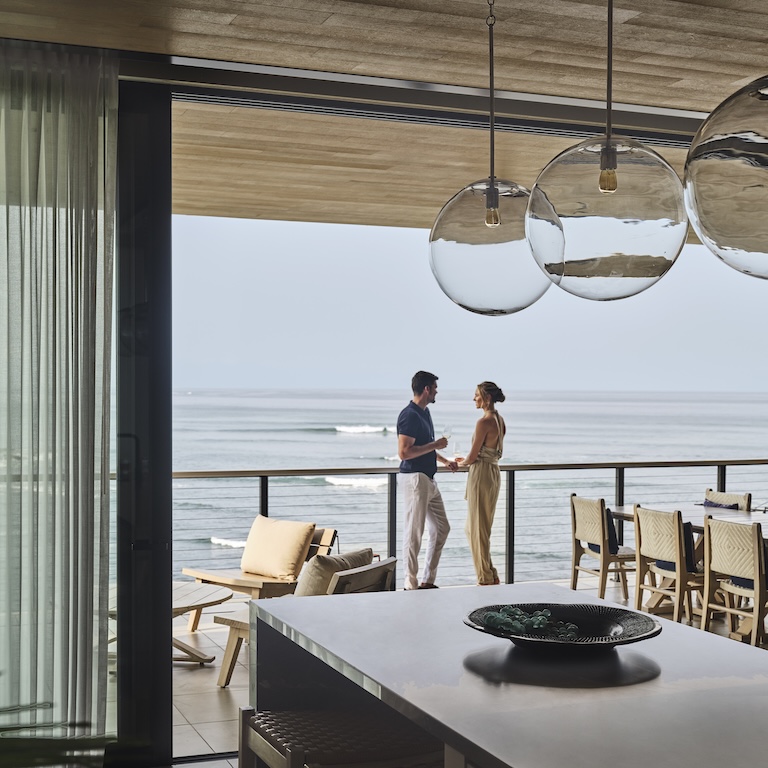 Man and woman on balcony overlooking ocean