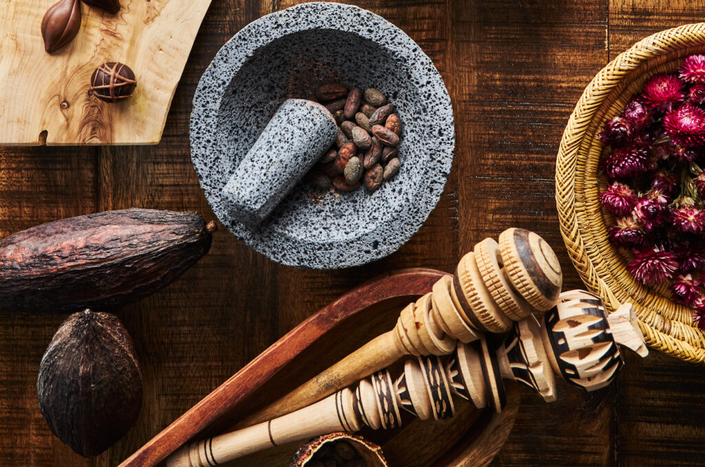 Up-close view of a mortar and pestle with flowers and cacao beans surrounding it through the chocolate immersion experience