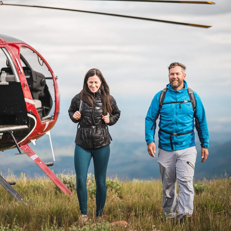 Man and woman walking next to helicopter