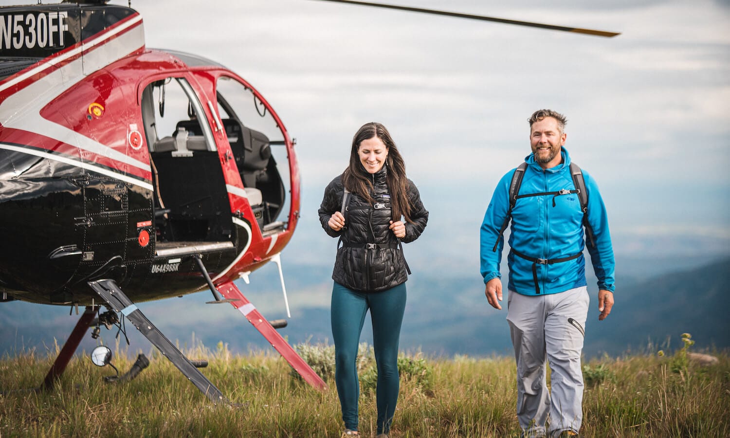 Man and woman walking next to helicopter